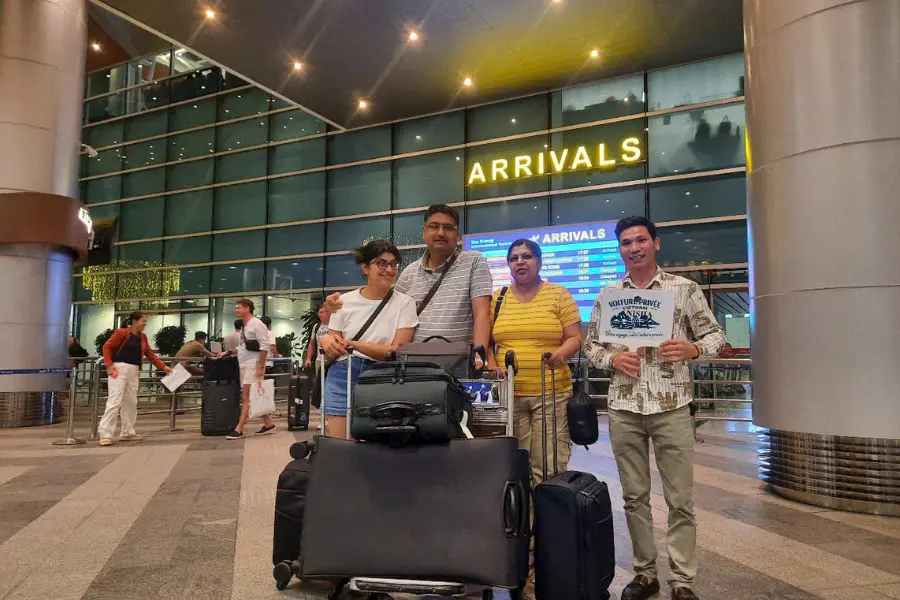 Chauffeur privé accueillant des voyageurs à l'aéroport avec assistance bagages au Vietnam.